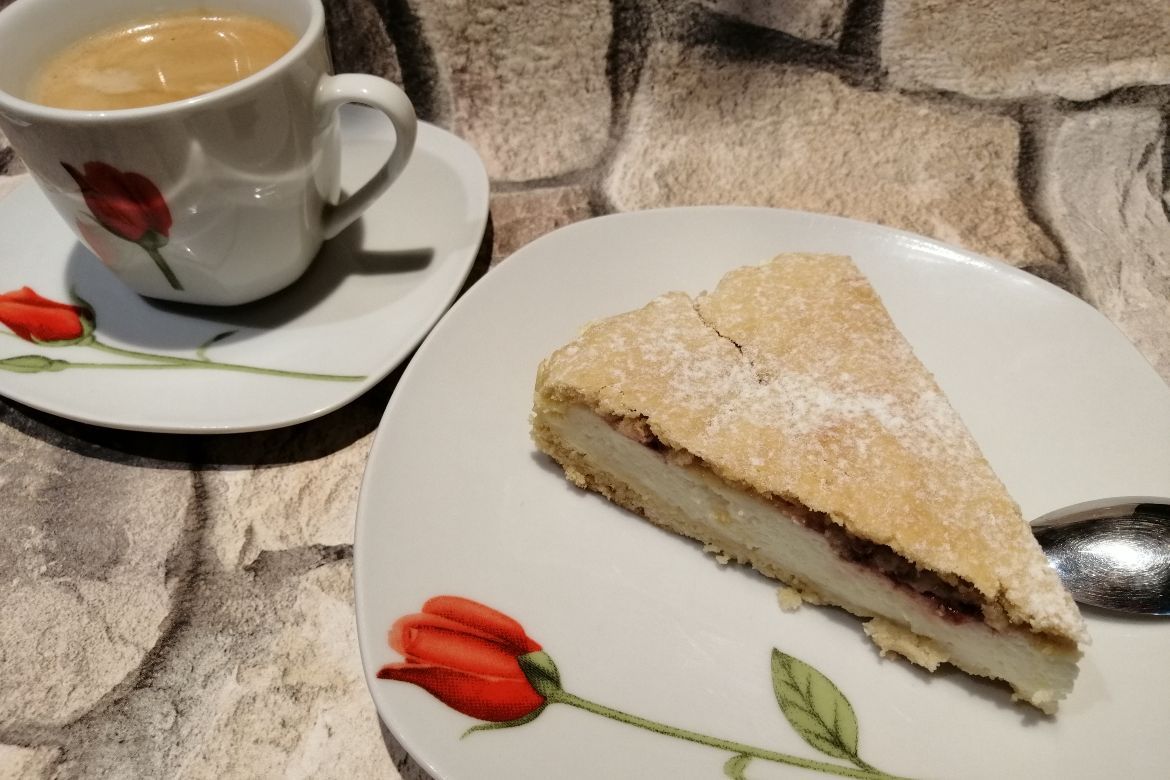 tvarohový koláč na bielom tanieri so šálkou kávy